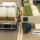 A garbage truck makes its way through a neighborhood emptying garbage cans