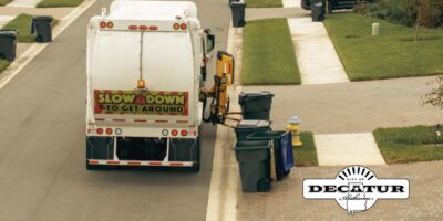 A garbage truck makes its way through a neighborhood emptying garbage cans