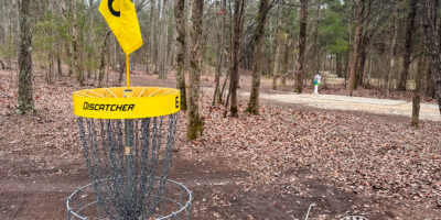 플라잉 드래곤 디스크 골프 코스의 디스크 골프 바스켓에 노란색 테두리와 노란색 홀 번호 깃발이 추가되었습니다.