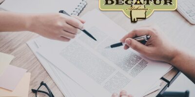 a stock picture of two hands that are holding pens and pointed at a piece of paper.
